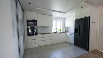 A modern kitchen with white cabinetry, a black refrigerator, and a built-in oven.
