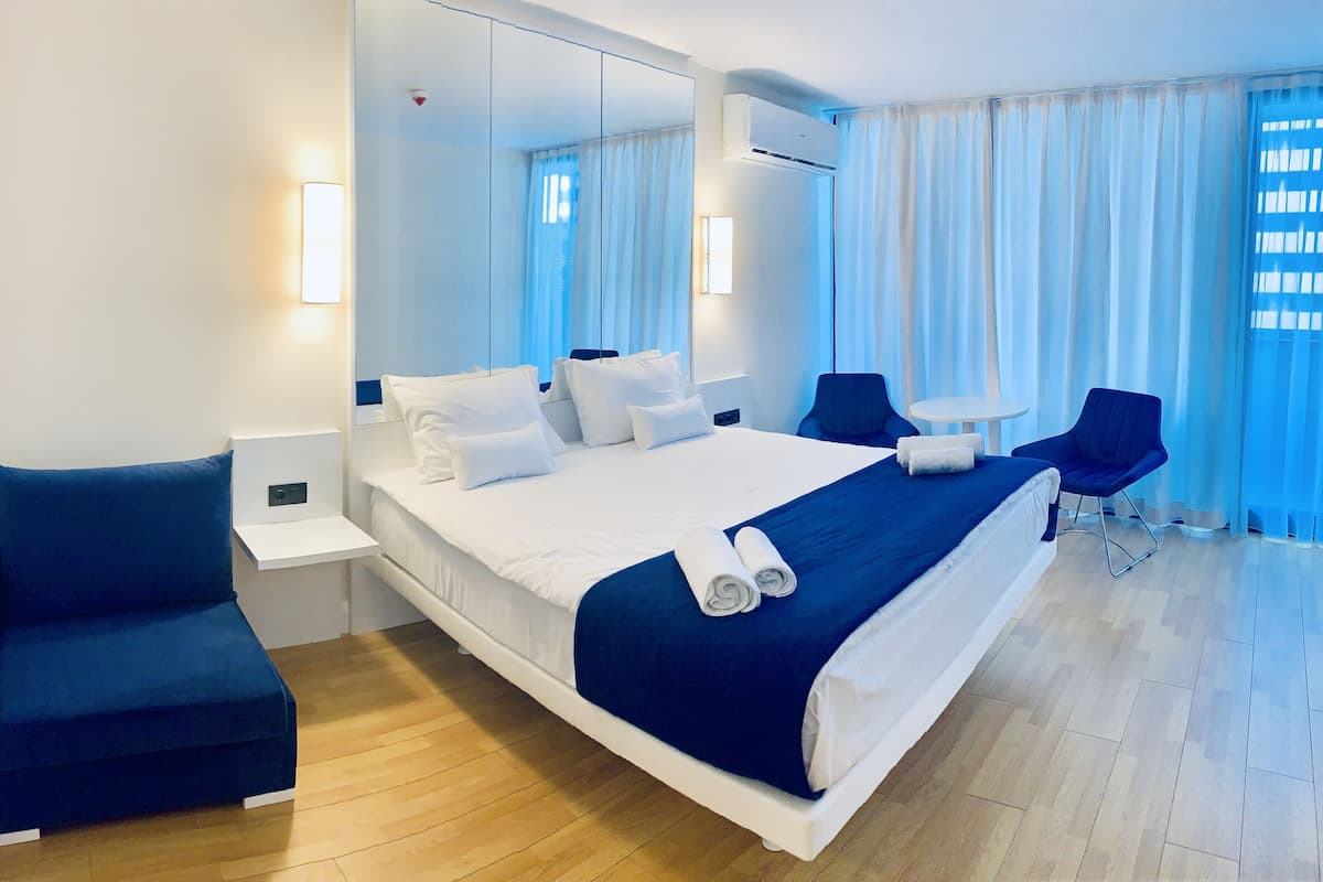 Een hotelkamer met een groot bed, twee nachtkastjes, een bureau, een stoel en een klein tafeltje.