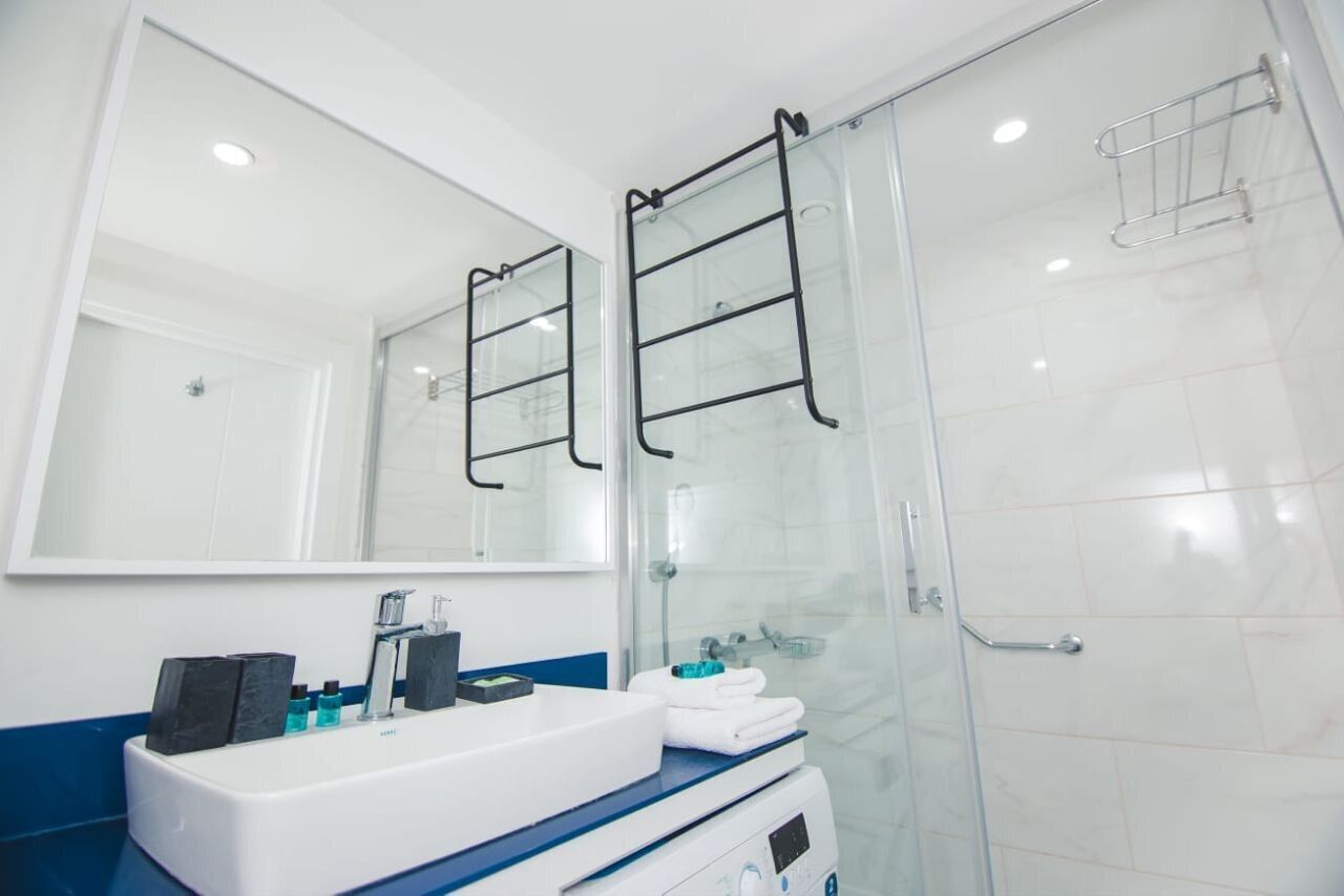 A modern bathroom with a white sink, mirror, and glass shower enclosure.