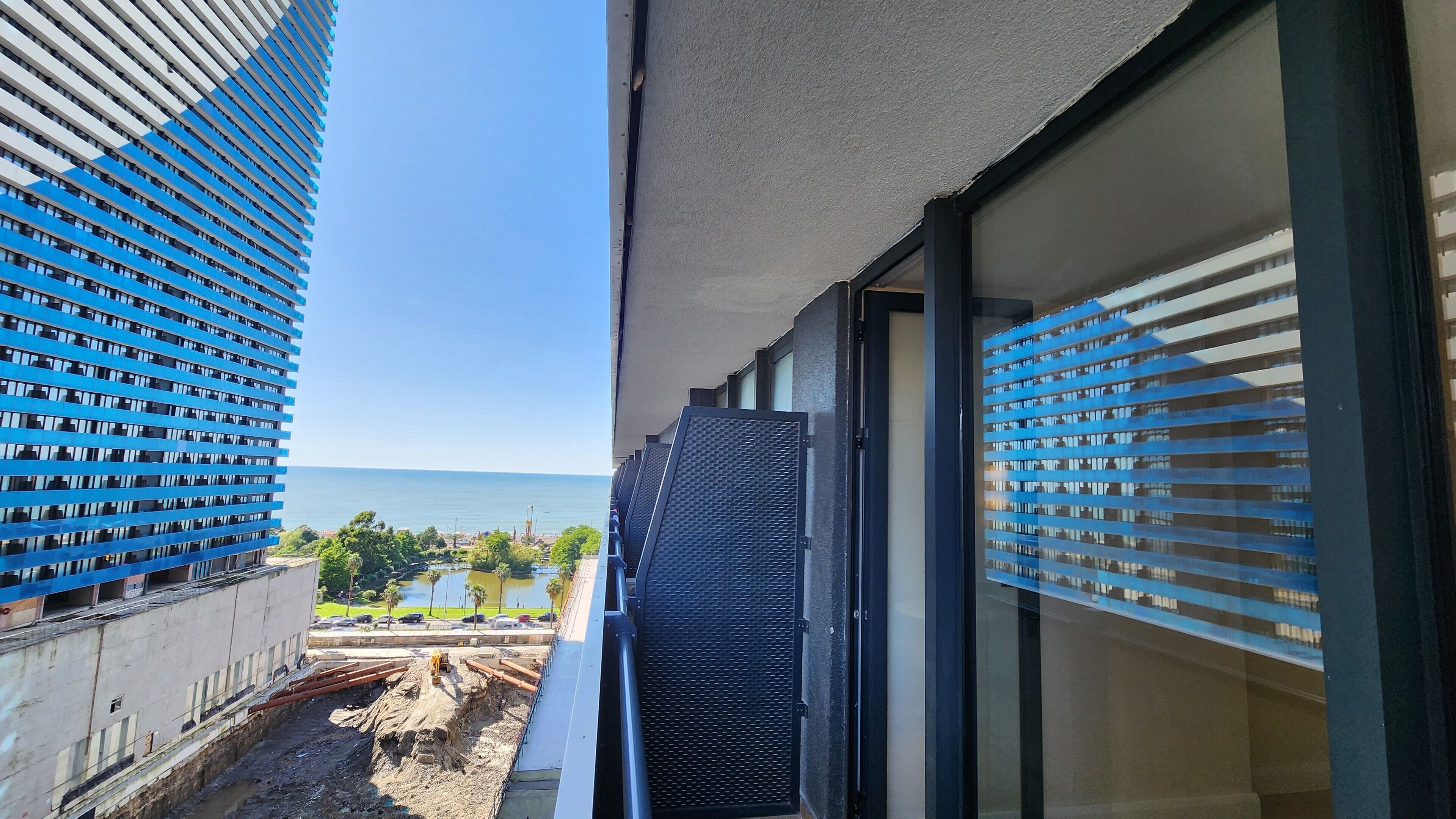 Un edificio de gran altura con vistas a una masa de agua y una obra en construcción abajo.
