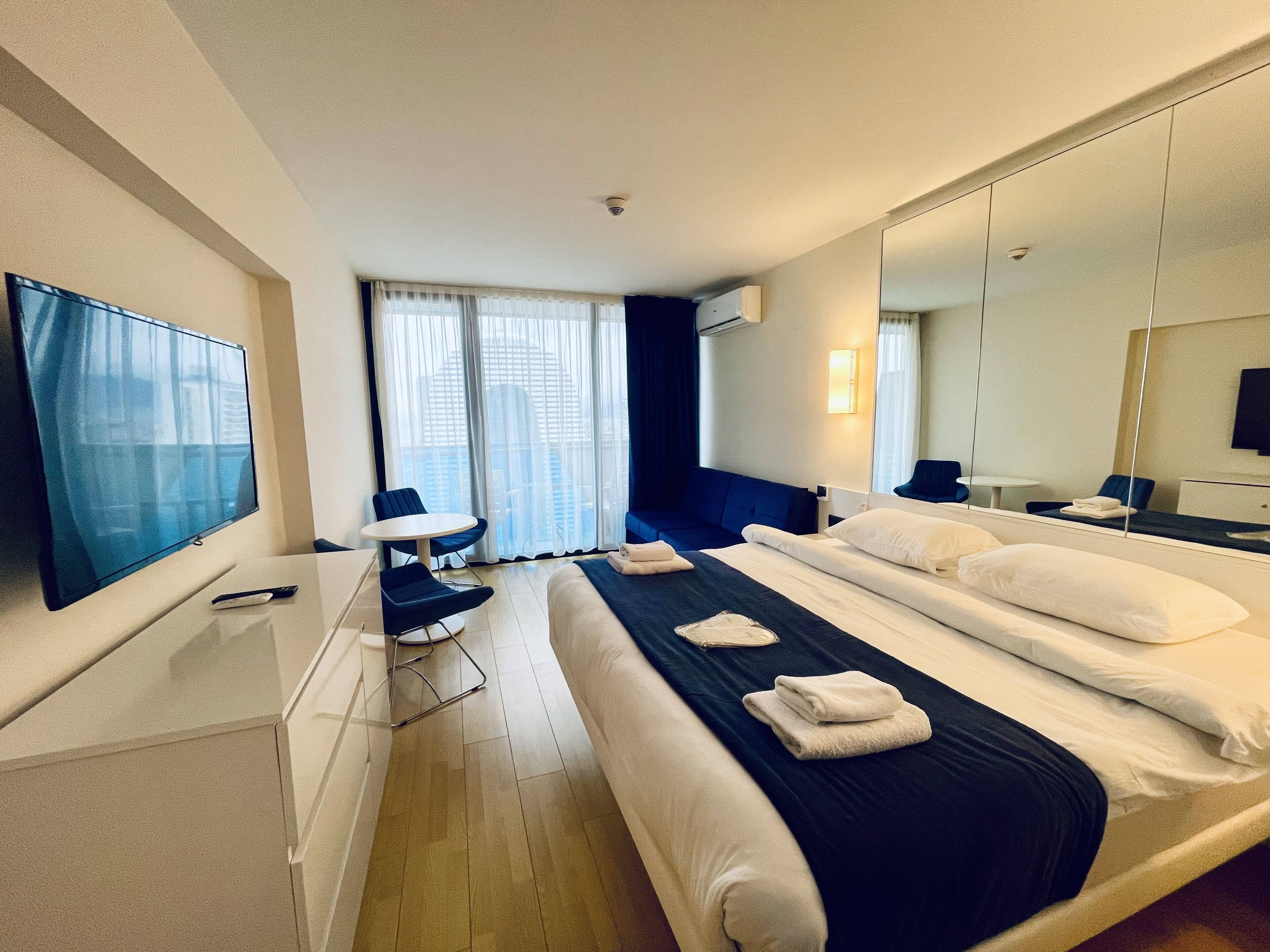 A hotel room with a bed, a TV, a desk, and a chair.