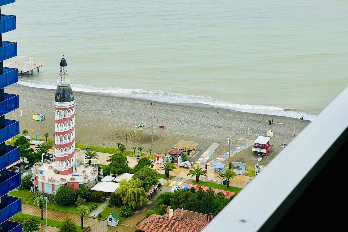 Kustgezicht met een toren, strand en gebouwen.