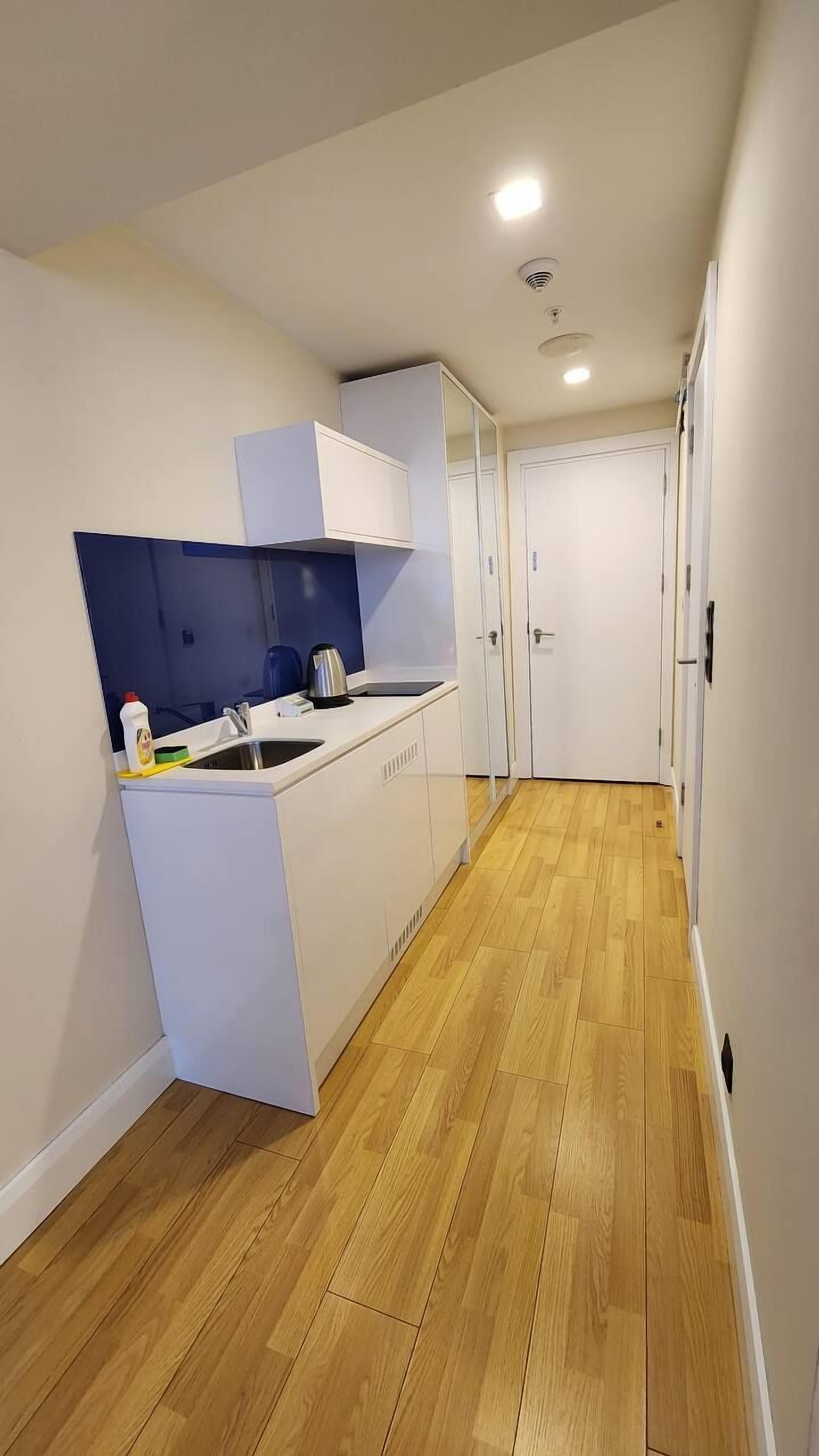 A modern kitchen with white cabinetry, a wooden floor, and a built-in oven.