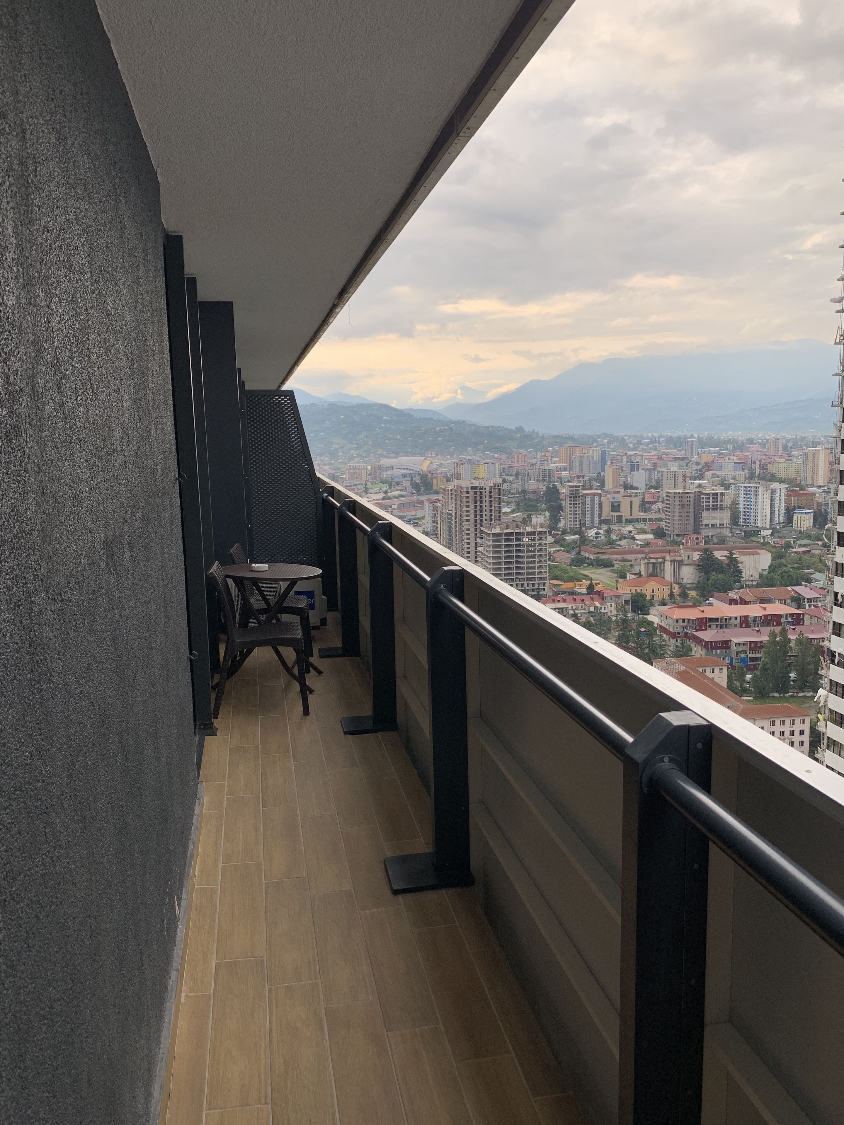 Un balcón con vistas a un paisaje urbano, que incluye edificios y montañas a lo lejos.