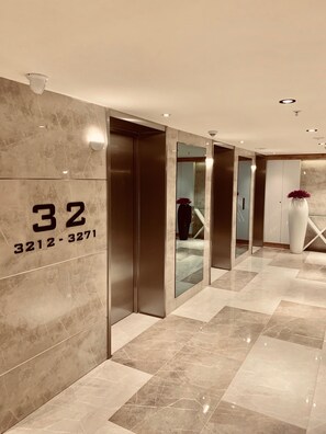 Un moderno vestíbulo de hotel con piso de mármol, un espejo grande y una recepción con un jarrón de flores.