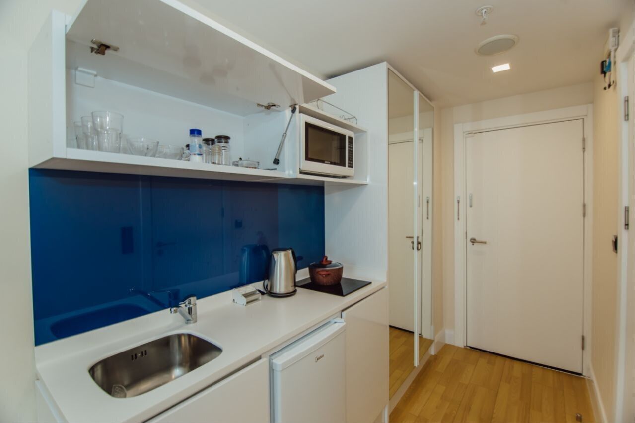 A compact kitchen with a built-in microwave, a sink, and a small refrigerator.