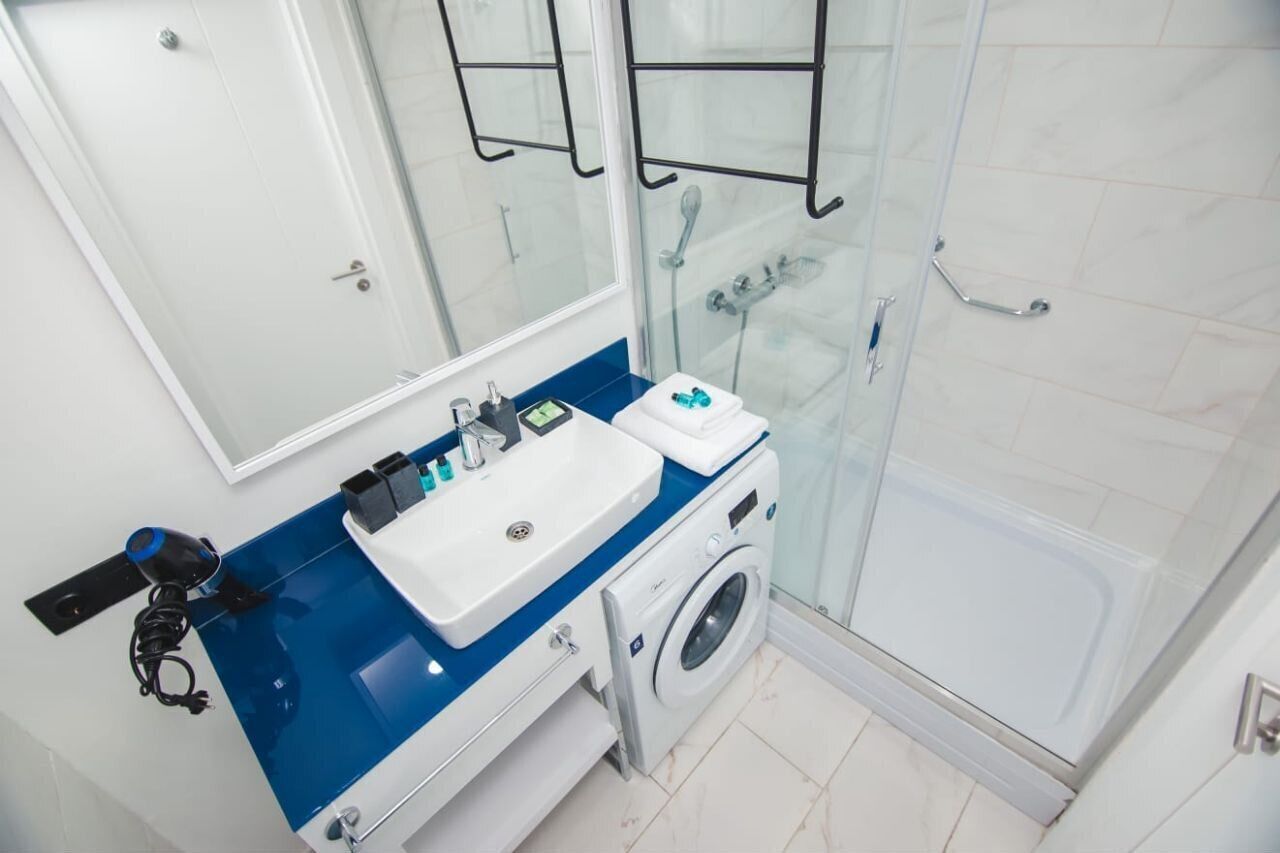 Ein modernes Badezimmer mit Duschkabine aus Glas, integriertem Waschbecken und Waschmaschine.