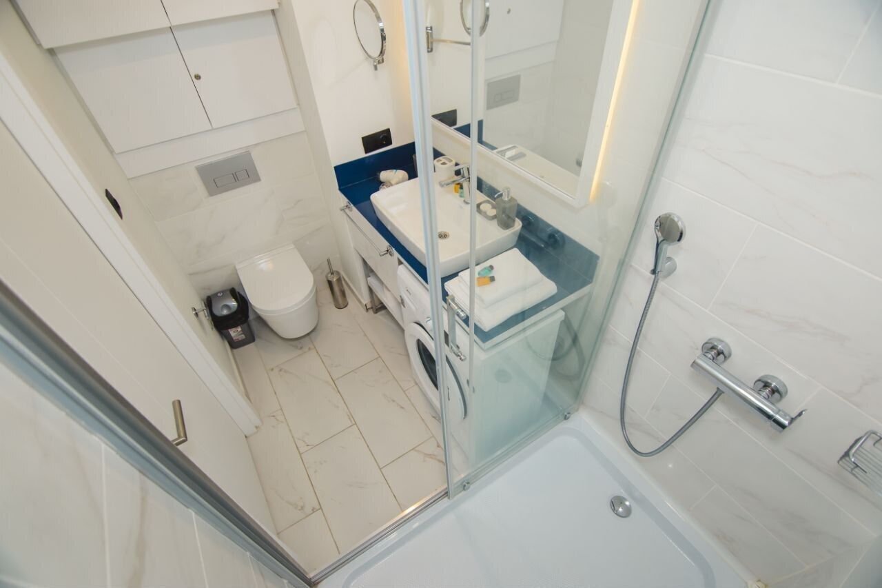 Une salle de bain moderne avec une douche à parois de verre, un lavabo blanc et un plan de toilette bleu.