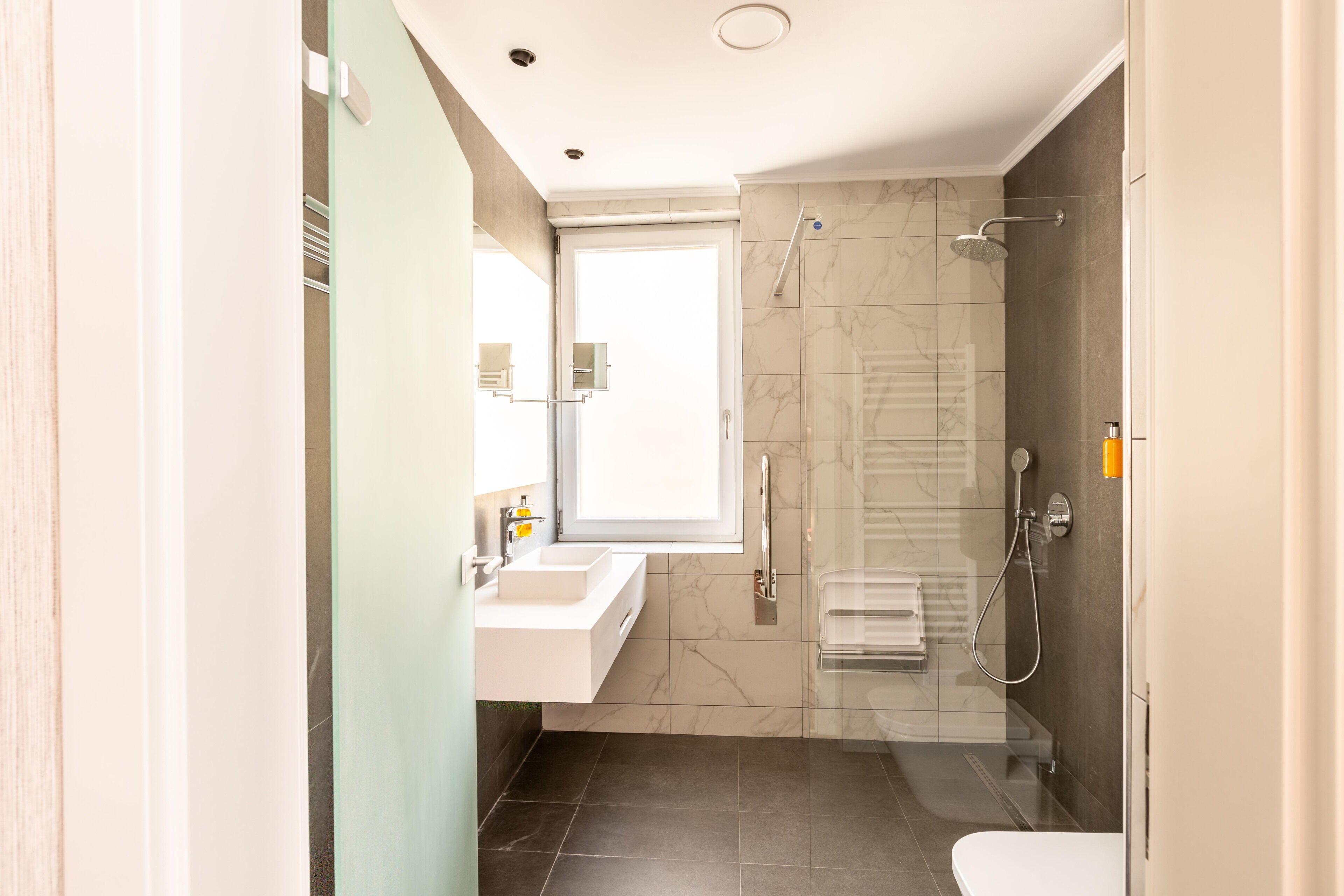 Une salle de bain moderne avec une douche à parois de verre, un lavabo blanc et des toilettes.