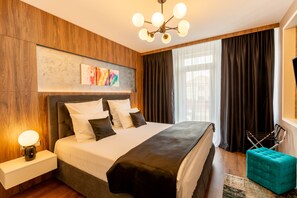 Une chambre d’hôtel moderne, dotée d’un grand lit, d’une table de chevet avec une lampe, d’une œuvre d’art accrochée au mur et offrant une vue sur la ville grâce à de grandes fenêtres.