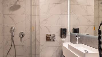 Un baño moderno con ducha de vidrio, inodoro blanco y tocador con espejo.