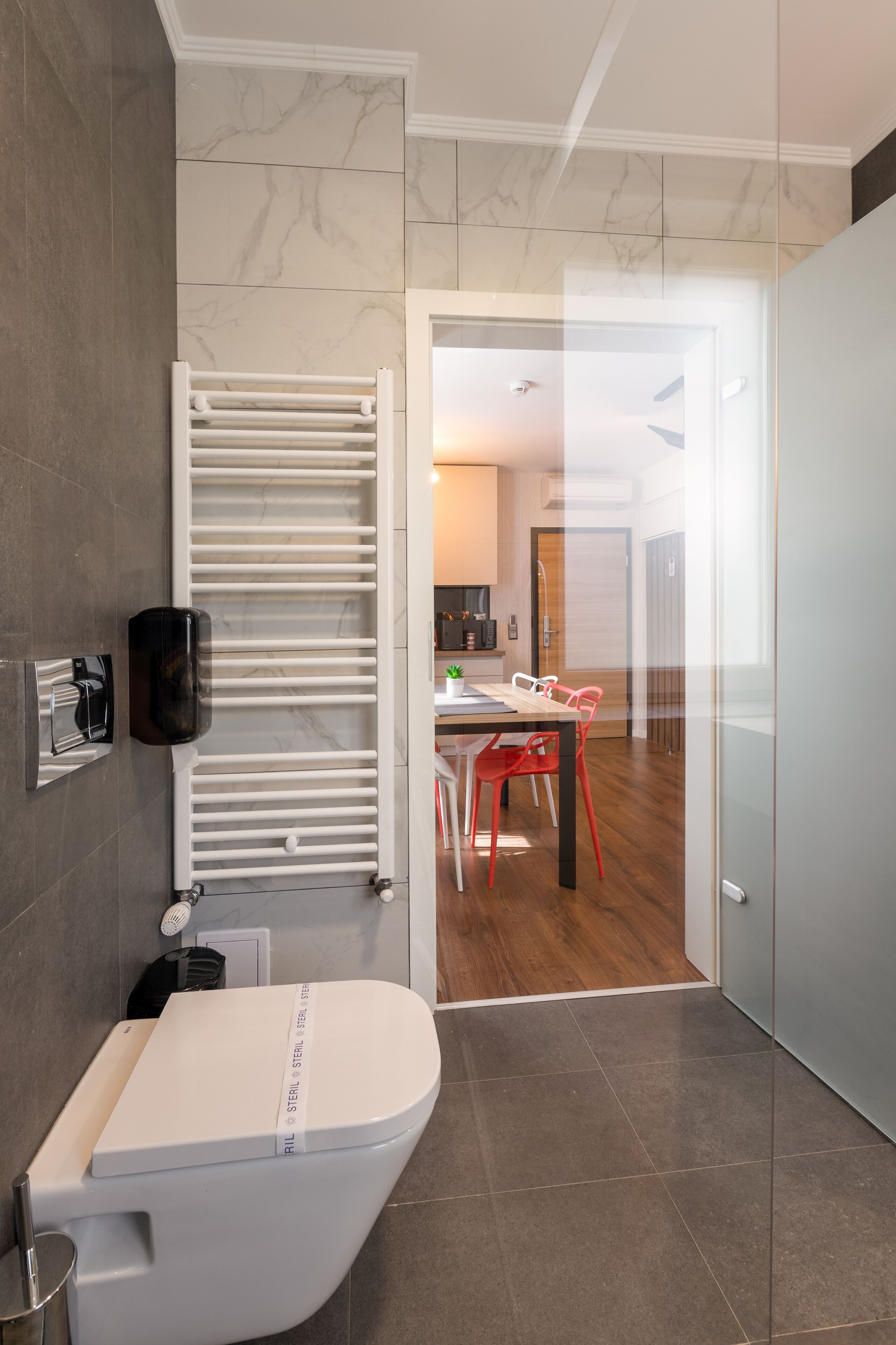 Une salle de bain moderne avec des toilettes, un porte-serviettes blanc et une cabine de douche en verre.