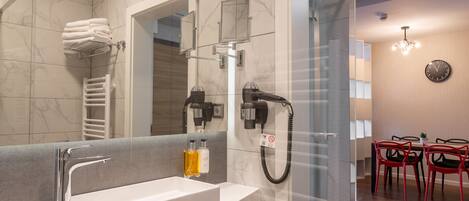 A modern bathroom with a large mirror, a white sink, and a glass shower enclosure.