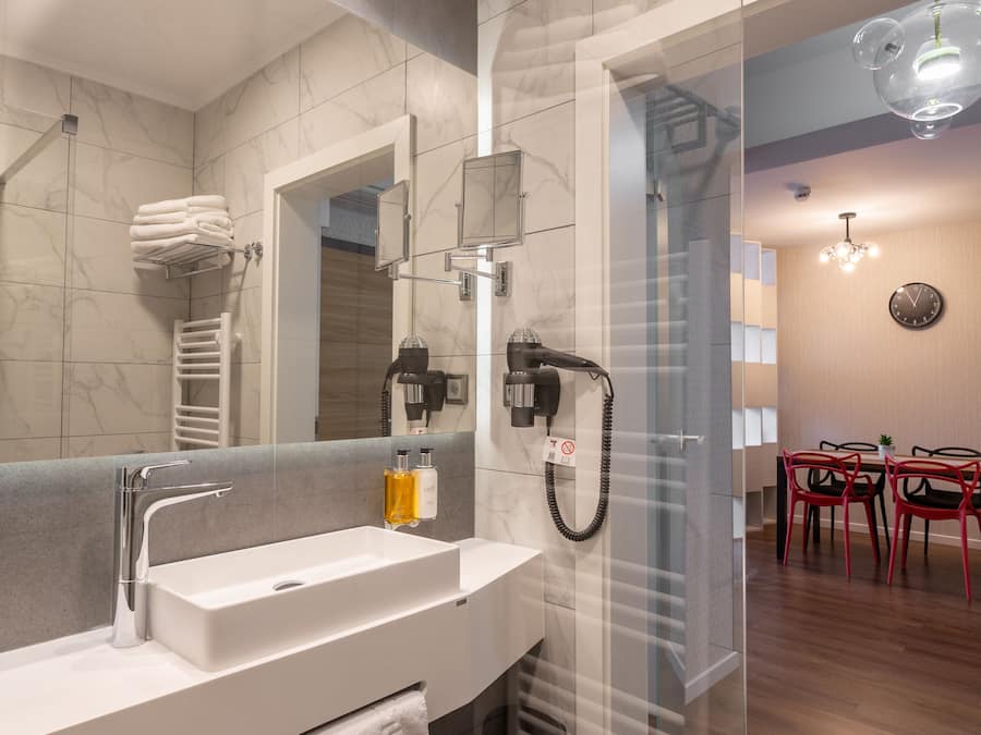 A modern bathroom with a large mirror, a white sink, and a glass shower enclosure.