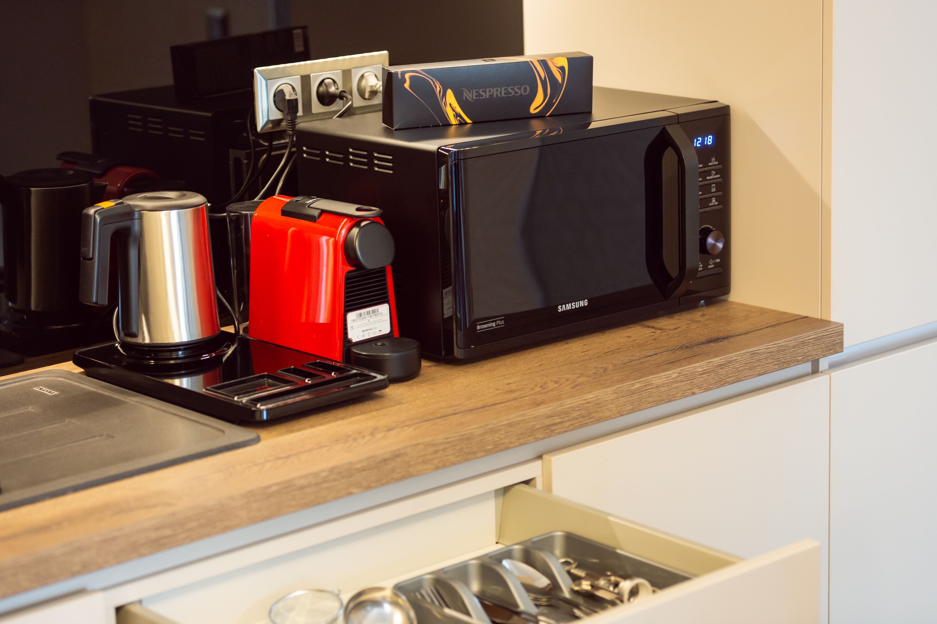 A kitchen with a coffee maker, a microwave, and a Nespresso machine on the counter.