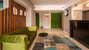 Un vestíbulo moderno con un sofá verde, un mostrador de recepción negro y una pared verde con un reloj.
