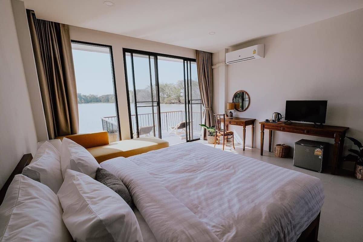A hotel room with a large bed, a desk, a television, and a view of the outdoors.