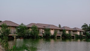 A row of bungalow-style buildings with sloped roofs, situated by a body of water. - Ploen Pirom (Bangkok)