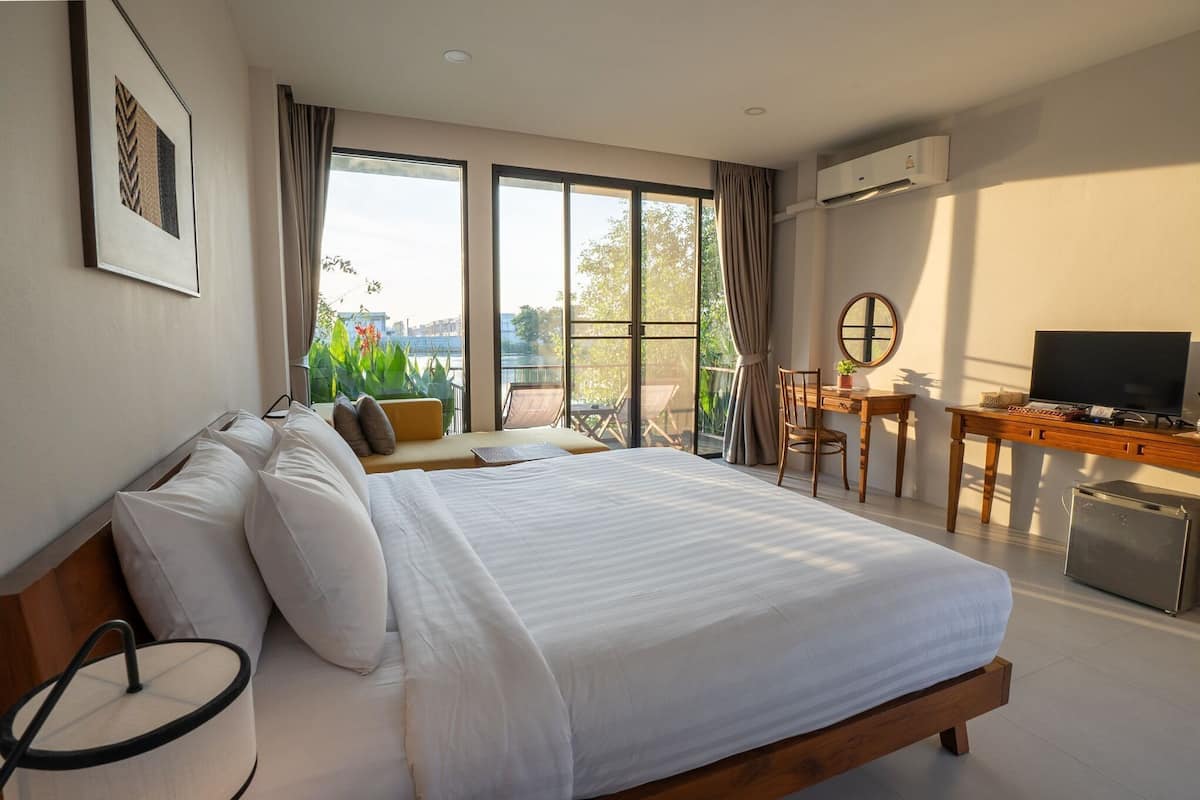 A bedroom with a large bed, a desk, a chair, and a television.