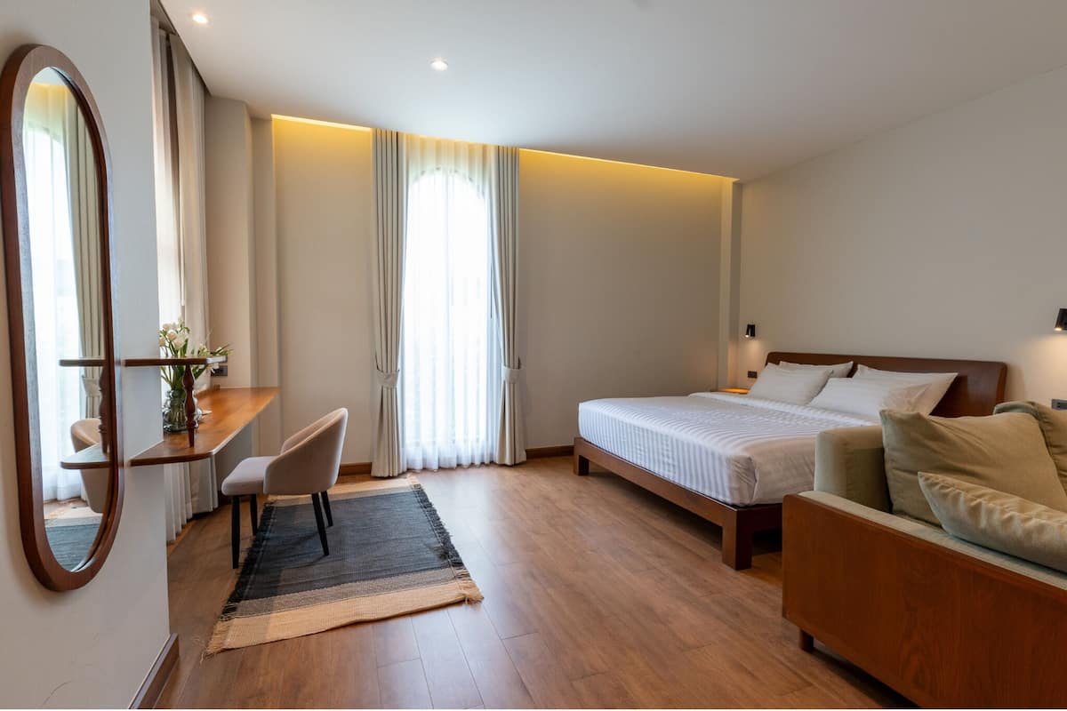 A hotel room with a bed, a sofa, a desk, and a chair.