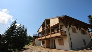 A two-story building with a balcony on the upper floor, surrounded by trees. - New apartment 6 ppl Les Saisies, terrace, parking (Hauteluce)