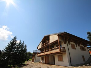A two-story building with a balcony on the upper floor, surrounded by trees.