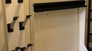 Un mur blanc auquel est fixée une étagère en métal noir.