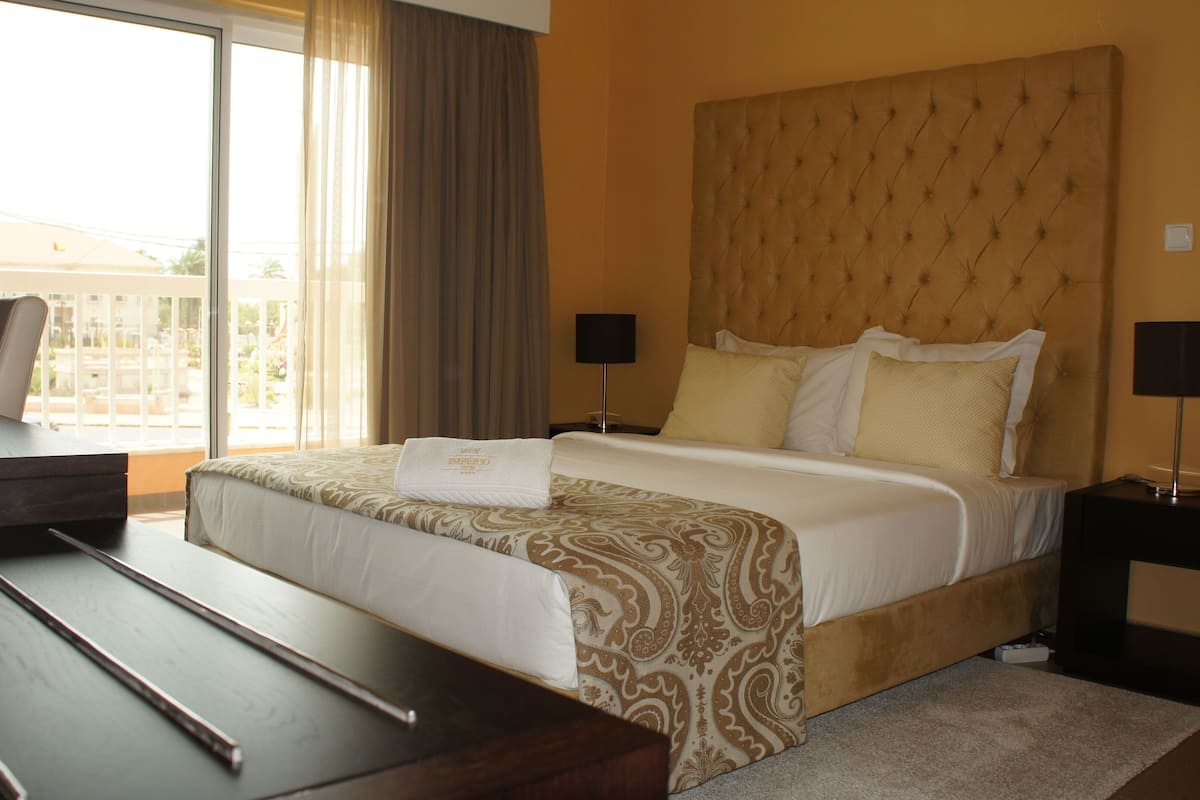 Una habitación de hotel con una cama grande, un escritorio y vistas al exterior.