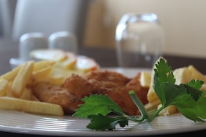 Un plato con pescado frito, papas fritas y una guarnición de perejil.