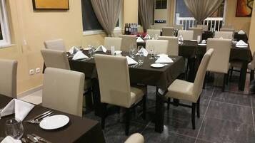 Een restaurant met gedekte tafels, stoelen en uitzicht op buiten.