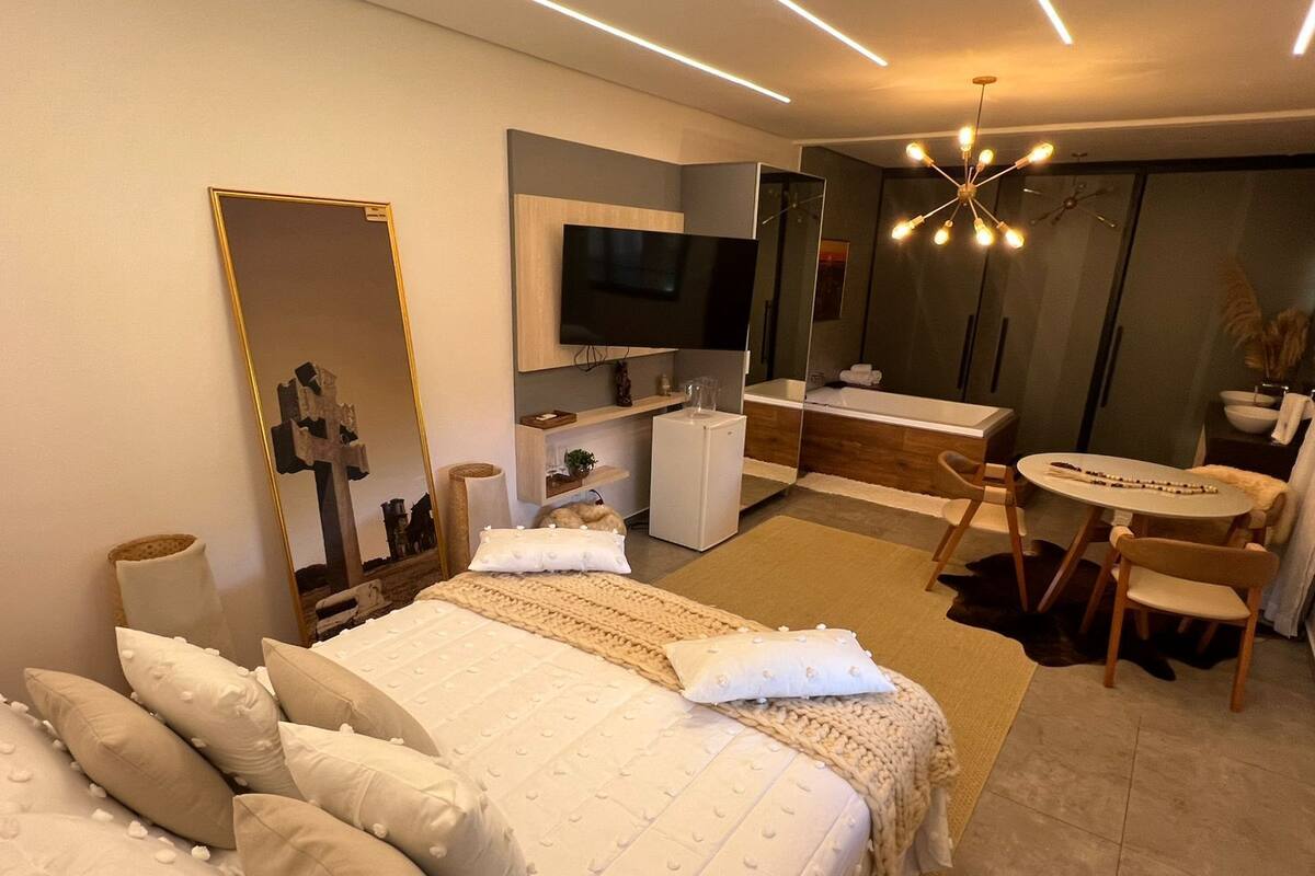 A modern hotel room with a large bed, a desk, and a bathroom.