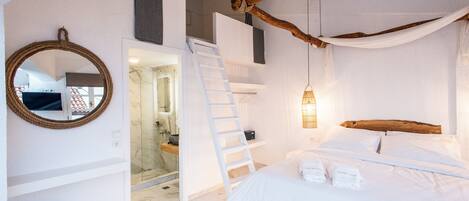 A bedroom with a bed, a wooden headboard, a ladder, a hanging light fixture, and a mirror on the wall.
