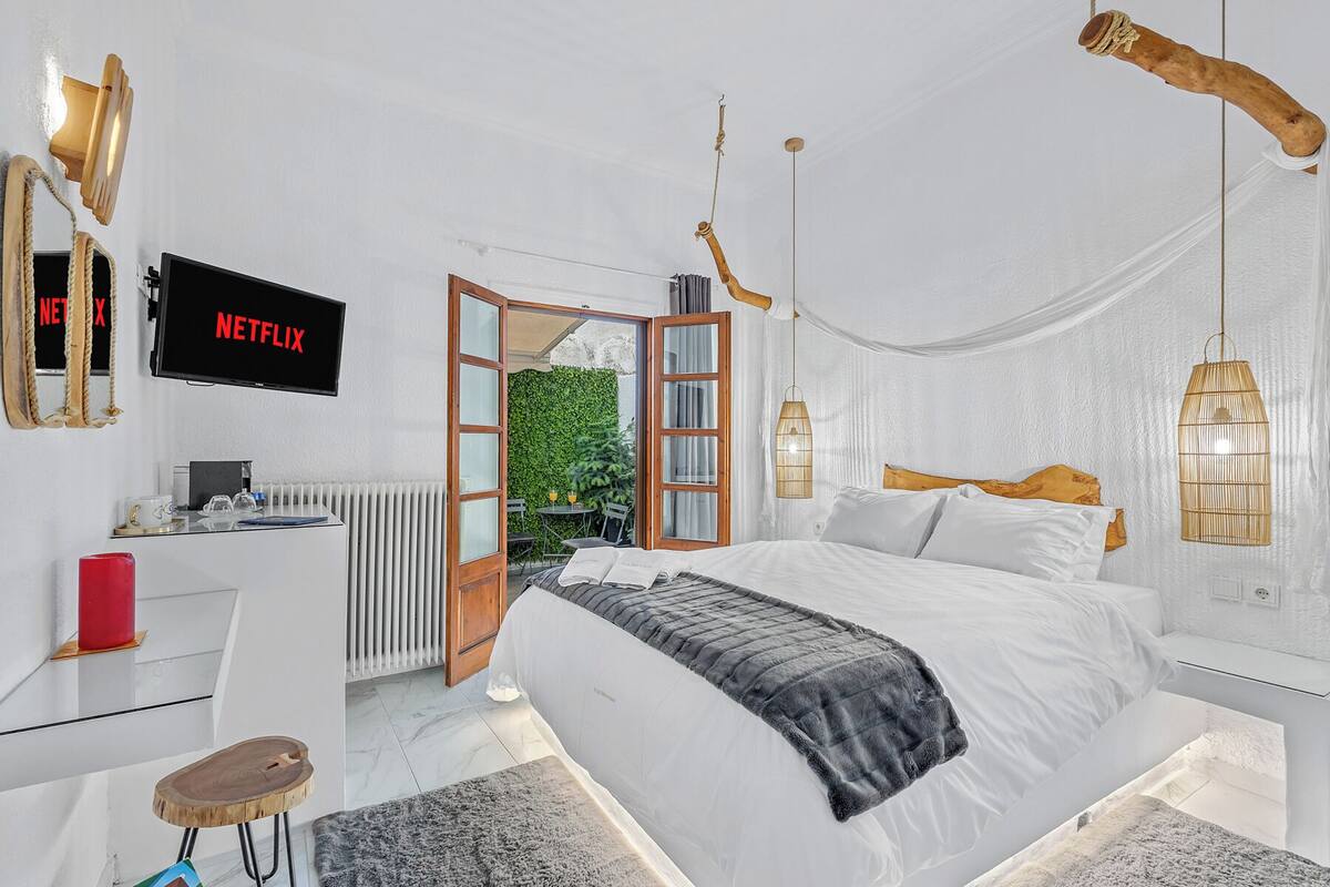 A modern bedroom with a bed, bedside table, and a TV displaying 'NETFLIX'.