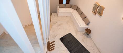 A modern interior with a curved white sofa, a dark rug, and a wooden bench.