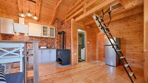 A wooden interior with a kitchen, a fireplace, a ladder, and a refrigerator. - Awesome home in Radakovo with sauna (Radakovo)