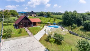 A residential area with a wooden house, a swimming pool, and a paved walkway. - Awesome home in Radakovo with sauna (Radakovo)