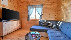 A cozy cabin interior with a wooden interior, a sofa, a television, and a small table with a remote control. - Awesome home in Radakovo with sauna (Radakovo)