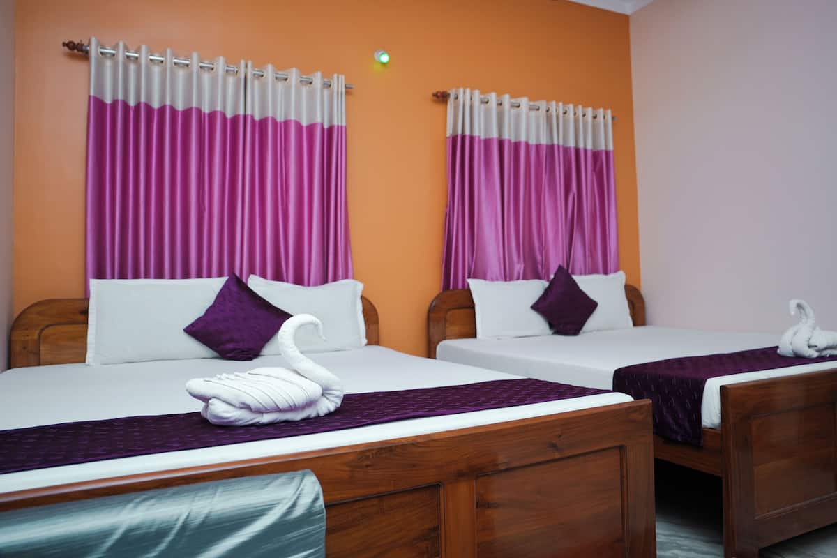 A hotel room with two beds, each with a wooden headboard, white bedding, purple pillows, and a purple blanket.