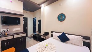 Una habitación de hotel con cama, escritorio, televisor, espejo y baño.