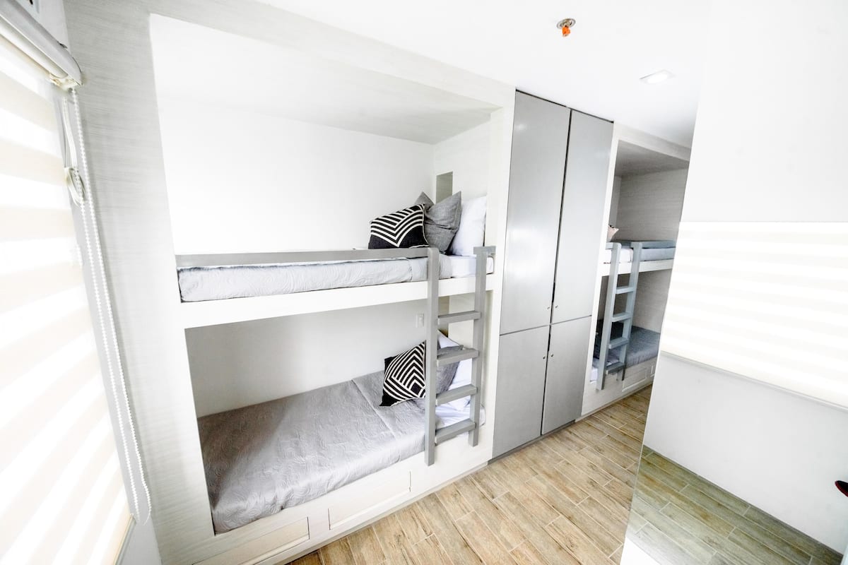 A bunk bed room with a wardrobe and a desk.
