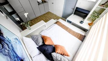 A modern bedroom with a bed, a TV, and a desk.