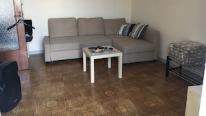 Un salon avec un canapé, une table basse et un tableau représentant un paysage urbain accroché au mur.