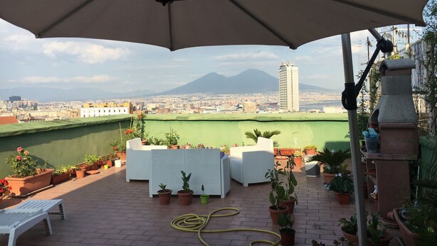Une terrasse extérieure offrant une vue sur le paysage urbain et sur une montagne.
