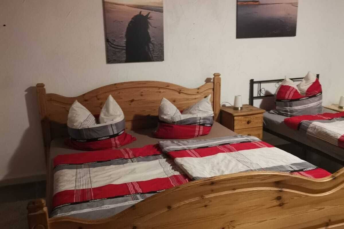 A single bed with a wooden headboard, a nightstand, and two wall-mounted paintings.