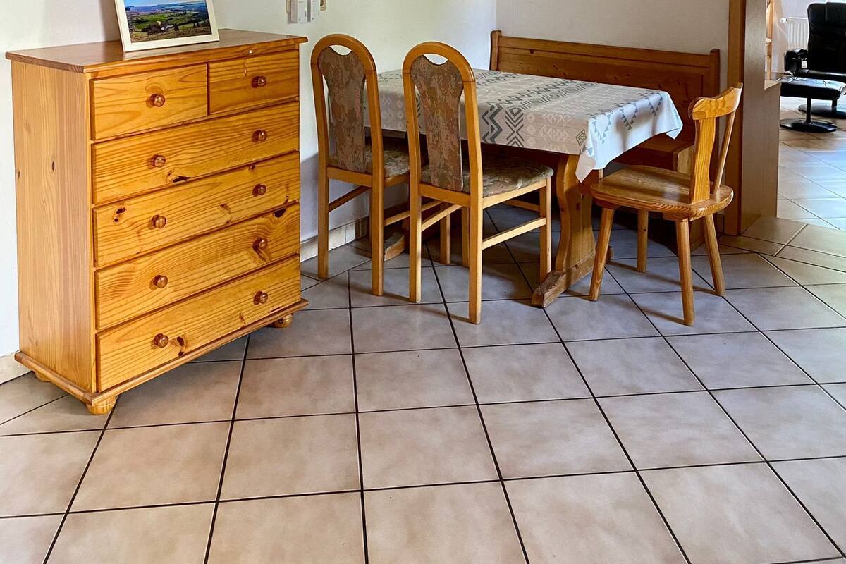 A dining area with a wooden table, chairs, and a cabinet. There are three framed pictures on the wall.