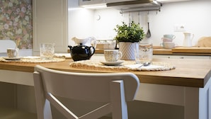 Ett matbord med bordsunderlägg, en svart kanna, en vit kanna och en krukväxt.