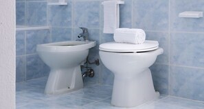 A bathroom with a bidet, toilet, and blue tiled walls. - JOIVY Little House (Como)