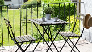 A wooden table with two chairs on a balcony, a potted plant, and a hat hanging on the wall. - JOIVY Little House (Como)