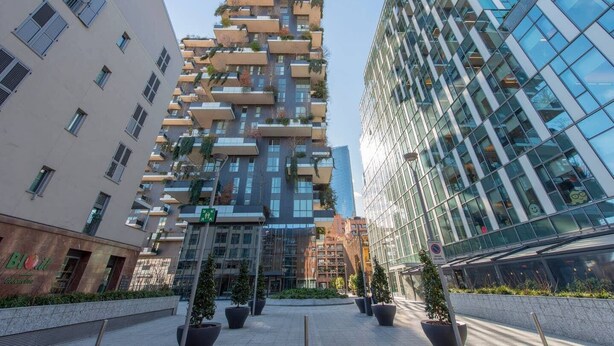 A modern building with a unique architectural design, featuring multiple balconies and a glass facade. - JOIVY Apartment, Window to the Vertical Forest (Milan)