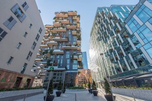 A modern building with a unique architectural design, featuring multiple balconies and a glass facade. - JOIVY Apartment, Window to the Vertical Forest (Milan)